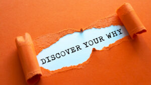 a torn orange paper with black text displaying: Discover your why