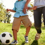 Child playing soccer with adult