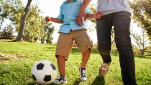 Child playing soccer with adult
