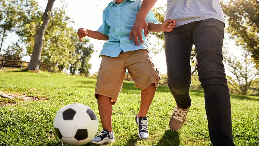 Child playing soccer with adult